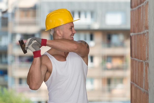 Un bel homme de la construction à l'aide d'un marteau pour clouer du bois ensemble