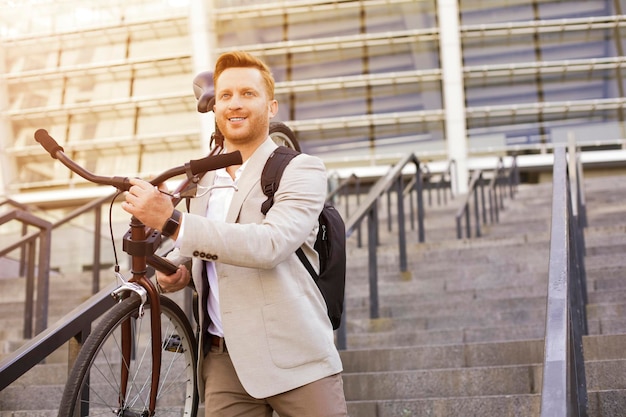 Bel homme en costume descendant les escaliers et tenant un vélo