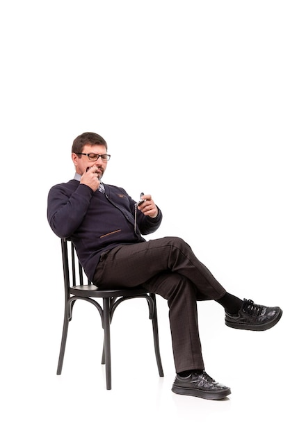 Un bel homme en costume et lunettes est assis avec une pipe pour fumer Fond blanc