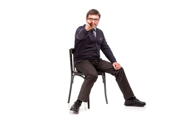 Un bel homme en costume et lunettes est assis avec une pipe pour fumer Fond blanc
