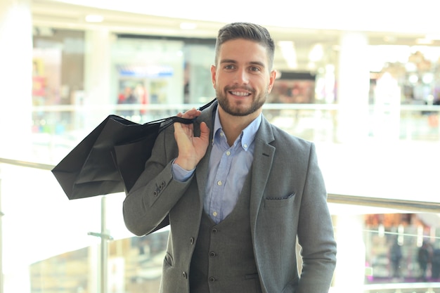 Bel homme en costume avec des sacs à provisions.