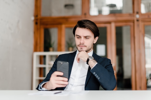 Bel homme en costume utilise le téléphone au bureau