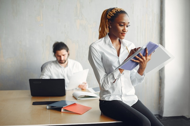 Bel homme dans une chemise blanche. Femme africaine avec partenaire. Guy avec un ordinateur portable.