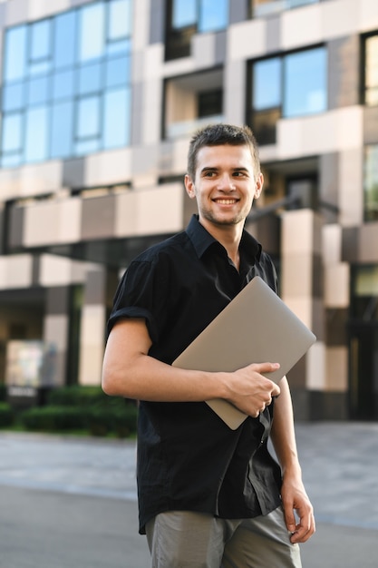 Bel homme dans une chemise noire avec un ordinateur portable