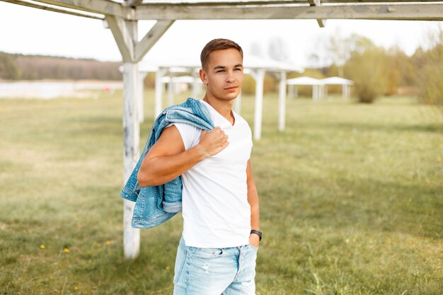 Bel homme dans un T-shirt blanc avec une veste en jean à l'extérieur