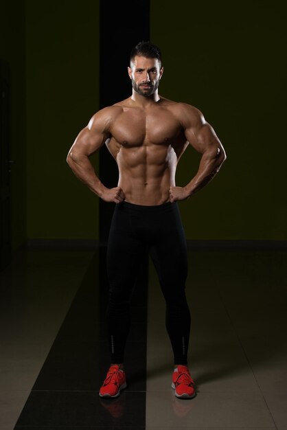 Bel homme debout fort dans la salle de gym et flexion des muscles musclé athlétique bodybuilder modèle de remise en forme posant après les exercices