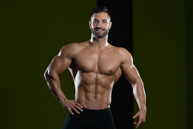 Bel homme debout fort dans la salle de gym et flexion des muscles musclé athlétique bodybuilder modèle de remise en forme posant après les exercices