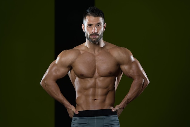 Bel homme debout fort dans la salle de gym et flexion des muscles musclé athlétique bodybuilder modèle de remise en forme posant après les exercices
