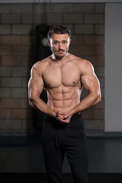 Bel homme debout fort dans la salle de gym et flexion des muscles musclé athlétique bodybuilder modèle de remise en forme posant après les exercices