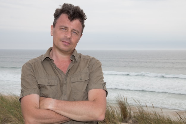 Bel homme debout sur la plage et regardant pensivement au loin