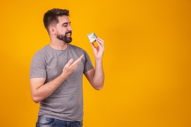 Bel homme dégustant un morceau de fromage gorgonzola sur fond jaune