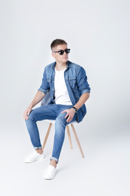 Photo bel homme en denim est assis sur une chaise