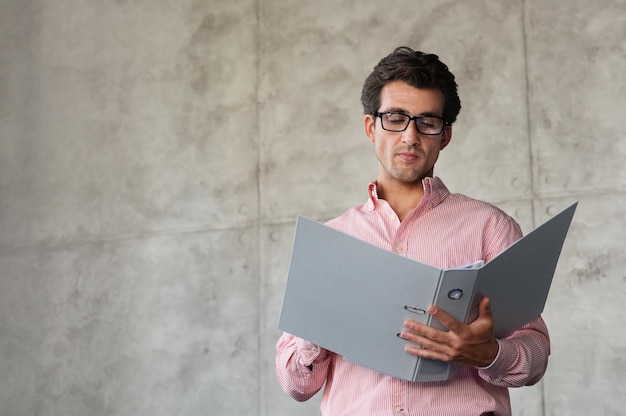 Bel homme directeur du millénaire vérifiant le rapport marketing au bureau