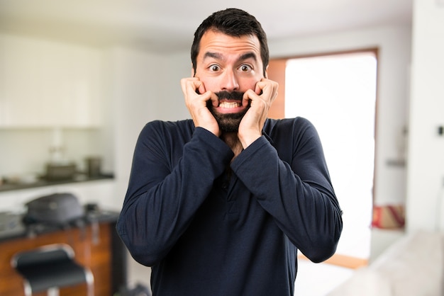 Bel homme effrayé avec barbe dans la maison