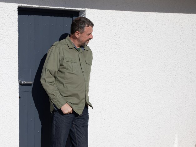 Bel homme élégant avec barbe debout extérieur devant la maison porte d'entrée grise