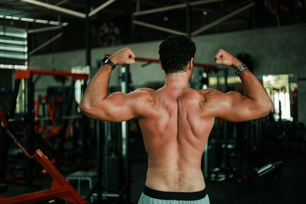 Bel homme exerce dans la salle de musculation avec un corps fort musculaire