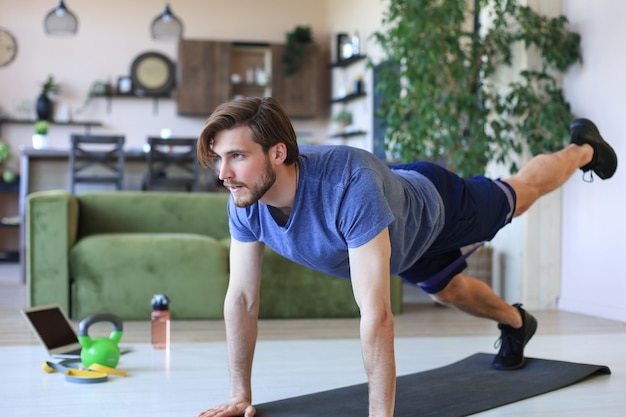 Bel homme faisant du sport à la maison pendant la quarantaine. Concept de vie saine.