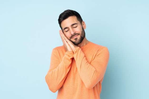 bel homme faisant le geste du sommeil dans une expression dorable sur bleu