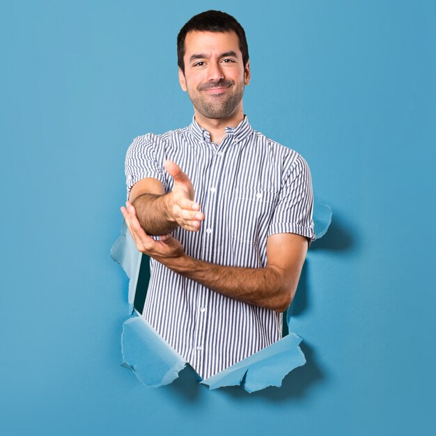 Bel homme faisant un marché à travers un trou de papier