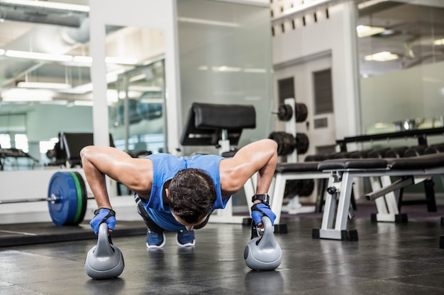 bel homme faisant des push ups avec kettlebells