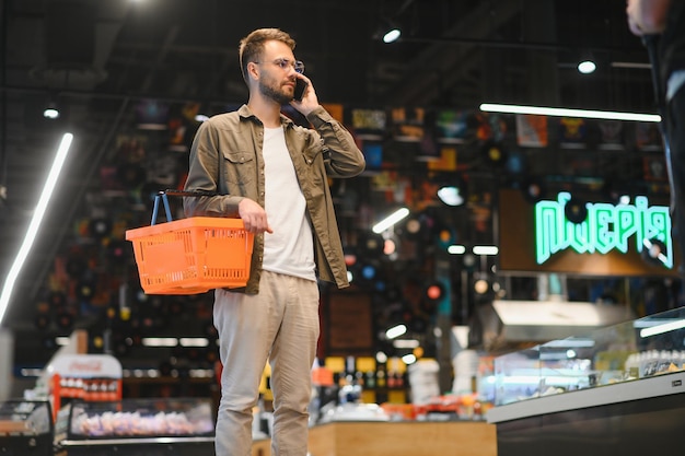 Un bel homme fait ses courses dans un supermarché.