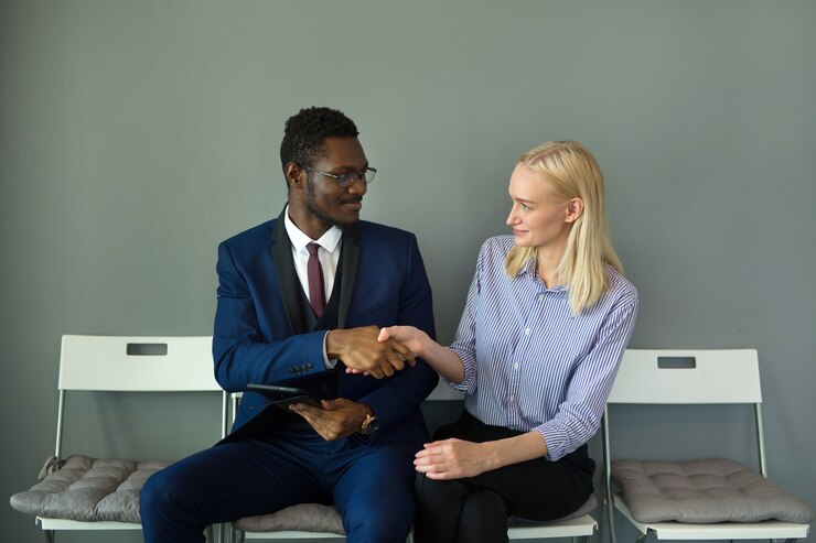 Photo bel homme et femme au bureau sur des chaises avec poignée de main