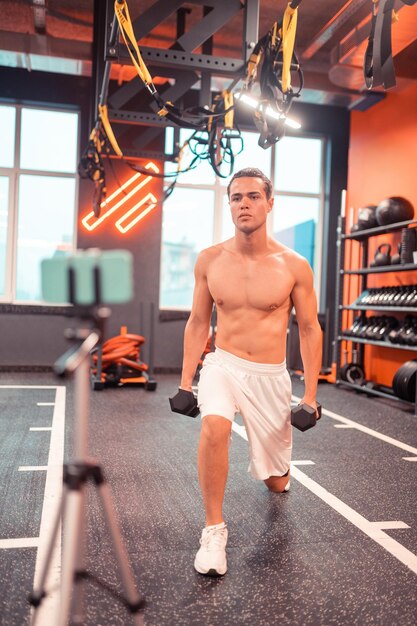 Bel homme en forme s'entraînant devant la caméra dans la salle de sport