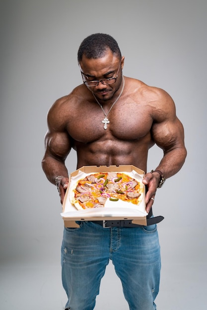 Bel homme fort avec un torse musclé et une pizza Bodybuilder nu affamé montrant une pizza