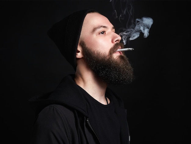 Bel homme fumeur barbu au chapeau