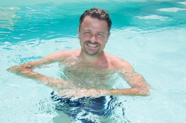 Bel homme gai dans la piscine