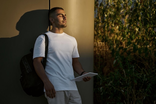 Bel homme heureux du Moyen-Orient avec les yeux tenant une tablette numérique, se détendre dans le parc