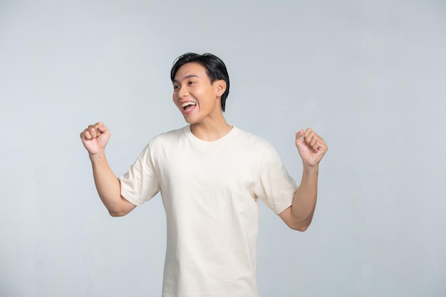 Bel homme heureux souriant excité faisant le geste du gagnant avec les bras levés