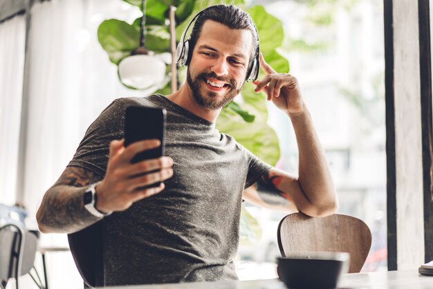 Bel homme hipster barbu à l'aide d'un smartphone