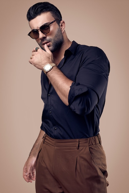 Bel homme hipster bronzé dans une chemise noire et des lunettes