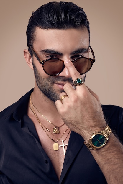 Photo bel homme hipster bronzé dans une chemise noire et des lunettes