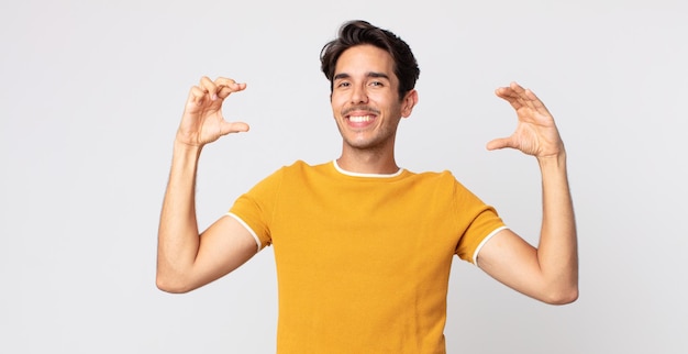 Bel Homme Hispanique Encadrant Ou Décrivant Son Propre Sourire Avec Les Deux Mains, L'air Positif Et Heureux, Concept De Bien-être