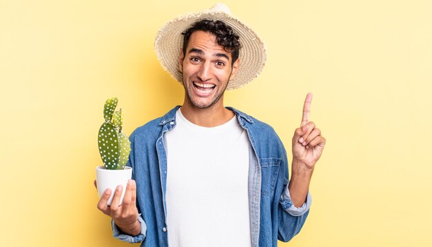 Bel homme hispanique se sentant comme un génie heureux et excité après avoir réalisé une idée de concept d'agriculteur et de cactus