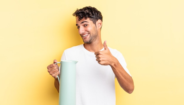 Bel homme hispanique se sentant fier, souriant positivement avec le pouce levé. concept de thermos à café