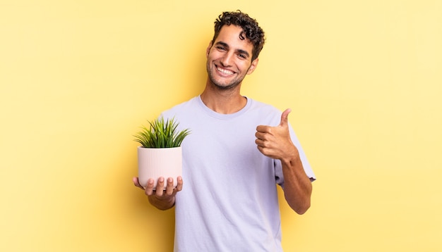 Bel homme hispanique se sentant fier, souriant positivement avec les pouces vers le haut. concept de plante décorative