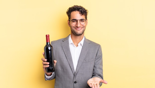 Bel homme hispanique souriant joyeusement avec amical et offrant et montrant un concept. concept de bouteille de vin