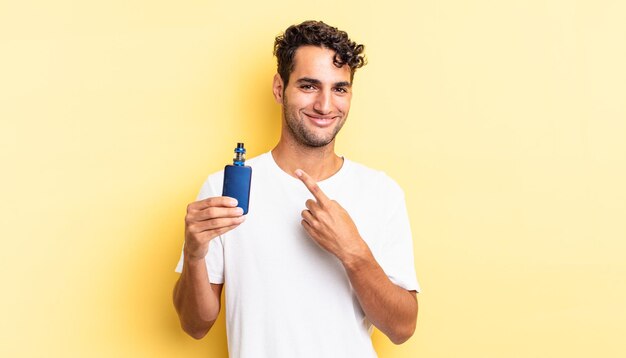 Bel homme hispanique souriant joyeusement, se sentant heureux et pointant sur le côté. concept de vaporisateur