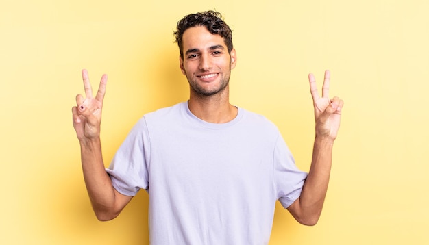 Bel homme hispanique souriant et semblant heureux, gesticulant la victoire ou la paix