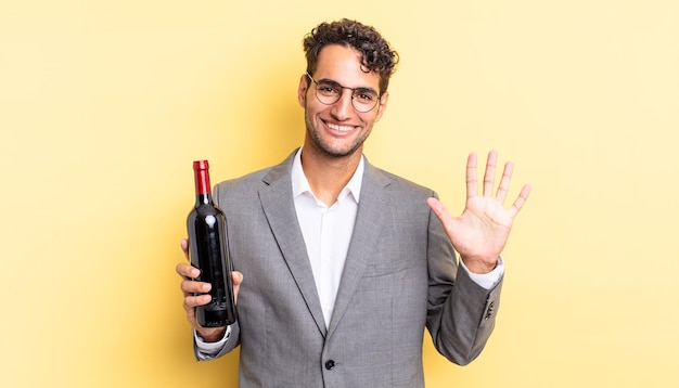 Bel homme hispanique souriant et sympathique montrant le concept de bouteille de vin numéro cinq