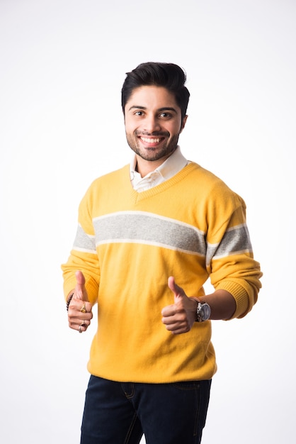 Un bel homme indien porte des vêtements d'hiver ou un pull en laine, présentant ou montrant. Debout sur fond blanc