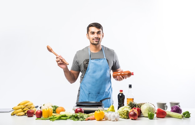 Bel homme indien souriant et joyeux préparant un repas dans la cuisine, nourriture saine, concept de cuisine.