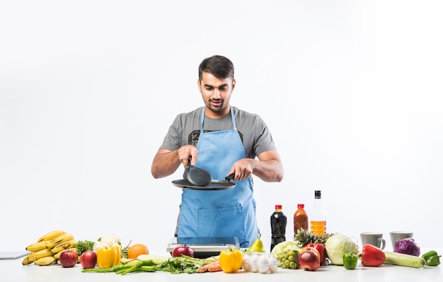 Bel homme indien souriant et joyeux préparant un repas dans la cuisine, nourriture saine, concept de cuisine.