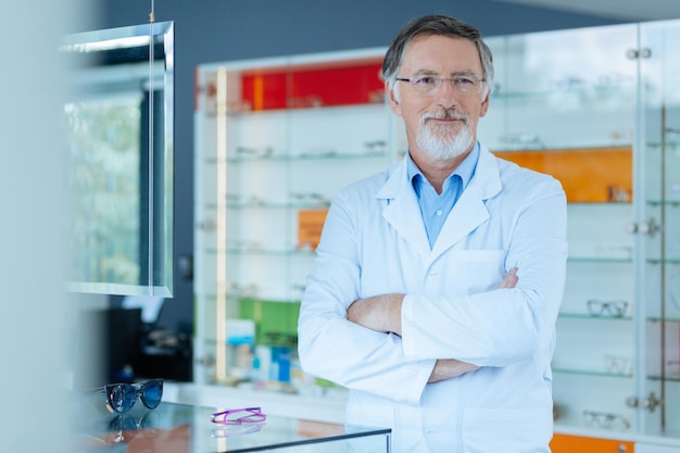 Bel homme intelligent souriant debout dans le magasin d'optique