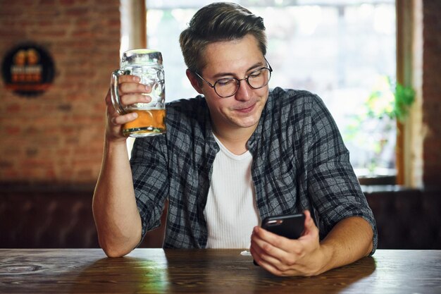 Bel homme intérieur en vêtements décontractés assis dans le pub