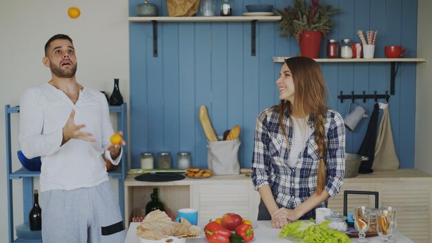 Bel homme jongle avec des fruits pour impressionner sa petite amie