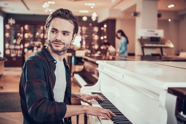 Bel homme joue du piano au magasin d'instruments de musique.